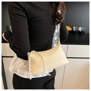 Close-up of beige shoulder bag featuring pleated texture and floral lace embroidery strap