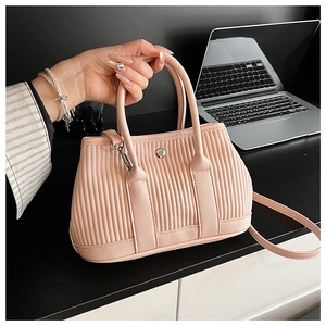 Detail of pink pleated bucket bag with metallic twist lock and detachable shoulder strap