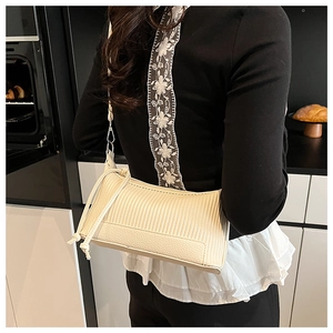 Detail of cream underarm bag showing pleated texture and litchi grain with side drawstring