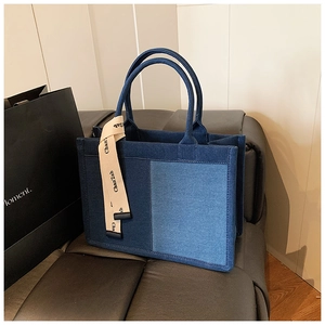 Close-up of two-tone denim tote bag with chic contrast panels and decorative fabric strap