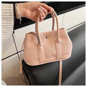 Close-up of pink pleated bucket bag with silver metal ring and adjustable shoulder strap