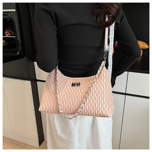 Detail of pink pleated handbag featuring a silver chain strap and metal turn-lock clasp
