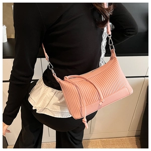 Détail du sac sous le bras en cuir grainé rose avec plis verticaux et longs glands en cuir