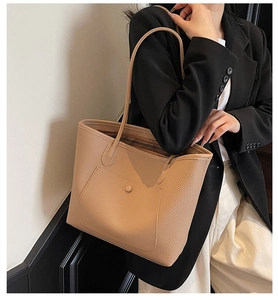 Detail of beige lychee pattern leather tote bag with a decorative round buckle front pocket