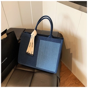 Detail of a large capacity color-block denim tote bag with decorative letter ribbon
