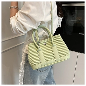 Detail of light green pleated bucket bag with silver round buckle and shoulder strap