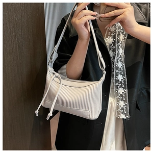 Detail of cream white pleated underarm bag featuring elegant fringe and pebbled leather