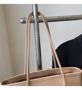Detail of smooth shoulder strap and zipper closure on beige lychee texture tote bag
