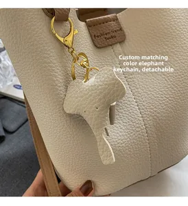 Close-up of beige lychee leather bucket bag with a detachable elephant-shaped charm detail