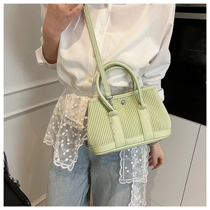 Detail of light green pleated bucket bag with metallic round buckle and thin shoulder strap
