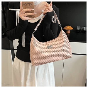 Detail of pink pleated shoulder bag featuring a silver twist lock and chain strap