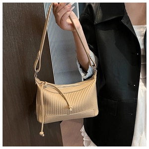 Detail of beige underarm bag with pleated texture and knotted drawstring on a model