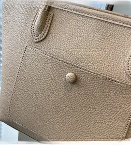 Close-up of beige faux leather tote bag showing litchi grain texture and precise stitching