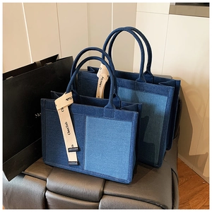 Detail of contrast patchwork denim tote bags in large and small sizes on a bench