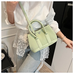Detail of light green pleated bucket bag showing metal buckle and smooth faux leather texture