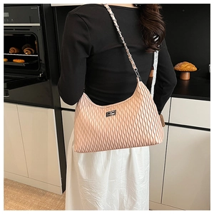Detail of pink pleated leather bag with silver twist lock and chain strap on shoulder