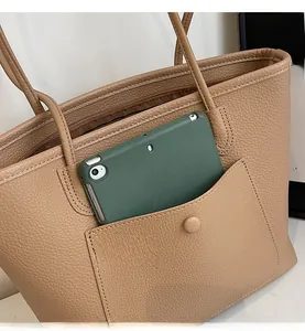 Detail of light brown tote bag featuring a front pocket for a tablet and lychee leather