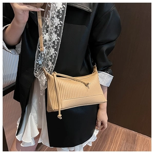 Detail of beige underarm bag showing vertical pleated texture and thin shoulder strap