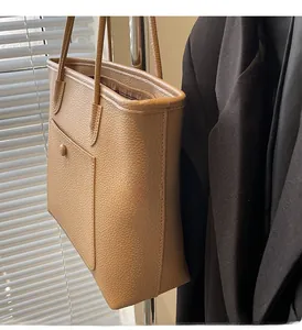 Detail of light brown lychee grain leather tote bag with functional front pocket