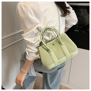Detail of light green pleated bucket bag with silver round buckle and shoulder strap