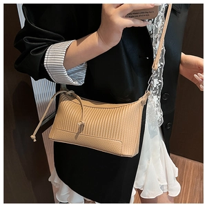 Détail du sac sous le bras beige avec gaufrage vertical et bandoulière réglable fine