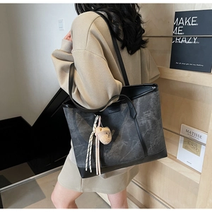 Detail of large tote bag with grey marble texture and plush bear charm on side