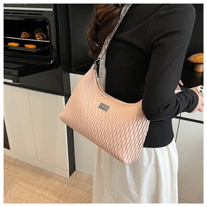 Pink wavy pleated hobo bag with silver rectangular buckle held by model in modern kitchen