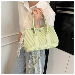 Detail of mint green pleated bucket bag featuring round metal buckle and top handle