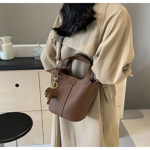 Detail of a brown lychee pattern bucket bag with a detachable strap and animal charm