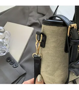 Close-up of luxury gold hardware and textured canvas fabric on a bucket bag