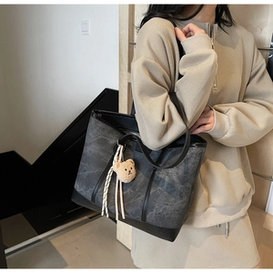 Detail of grey marble pattern tote bag with plush bear charm and black handles