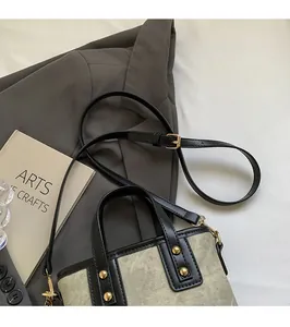 Detail of khaki canvas bucket bag with black leather trim and adjustable shoulder strap