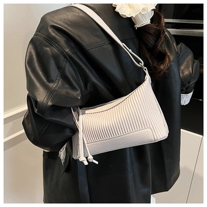Detail of cream pleated crossbody bag with pebble grain leather and decorative tassel
