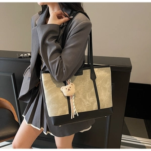 Detail of grey marble-patterned tote bag with black leather trim and plush bear charm