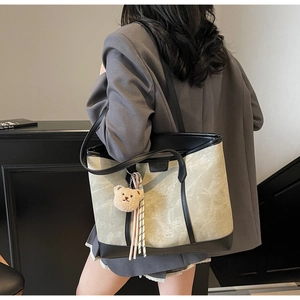 Side view of a canvas tote bag on a model featuring a cute bear charm and striped tassel