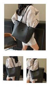 Detail of black pebbled leather tote bag showing the outer pocket and long shoulder straps