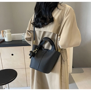 Rear view of model wearing a black litchi pattern bucket bag with golden hardware