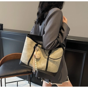 Detail of grey canvas tote bag with black leather trim and cute plush bear pendant