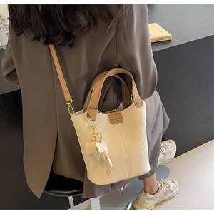 Detail of lychee textured leather bucket bag with white elephant charm and contrast trim