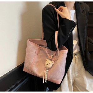 Detail of pink marble textured tote bag with cute bear charm worn by a model