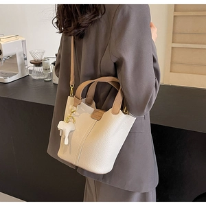 Detail of cream lychee texture bucket bag with brown contrast handle and elephant charm