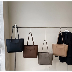 Detailed display of four minimalist tote bags in black brown grey and khaki hanging on rack