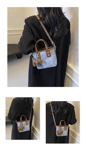 Detail of blue denim bucket bag with brown leather trim and cute puppy charm