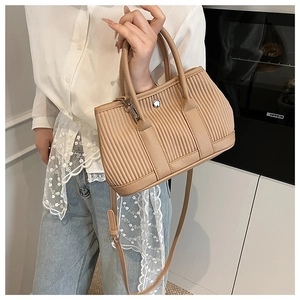 Detailed view of khaki pleated bucket bag showing vertical texture and leather handle