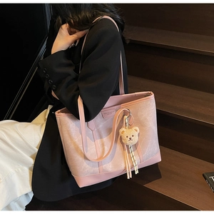 Close-up of pink tote bag with leather texture, bear charm and shoulder strap detail