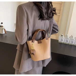 Lychee texture bucket bag with contrast handle and elephant charm shown in café setting