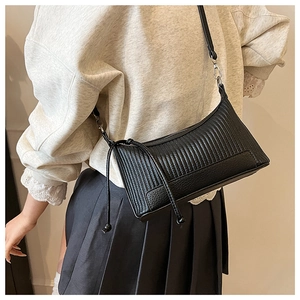 Detail of black quilted leather shoulder bag featuring pleated texture and silver metal hooks