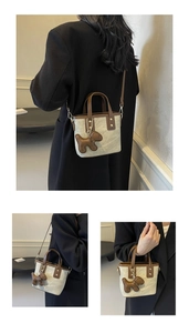 Detailed view of mini tote bag with textured beige fabric and brown leather trim accents