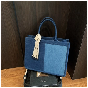 Detail of color-block denim tote bag with decorative printed ribbon and sturdy handles