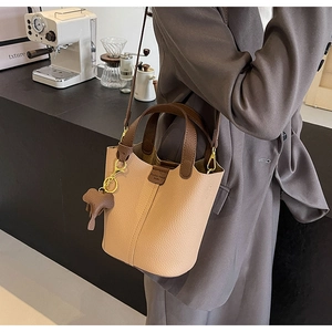 Detailed side view of two-tone bucket bag with litchi grain and elephant charm